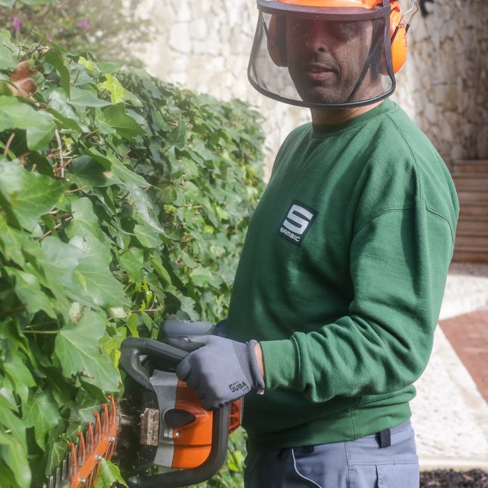 Técnino de jardinagem/espaços verdes a podar arbustos com uma máquina que poda