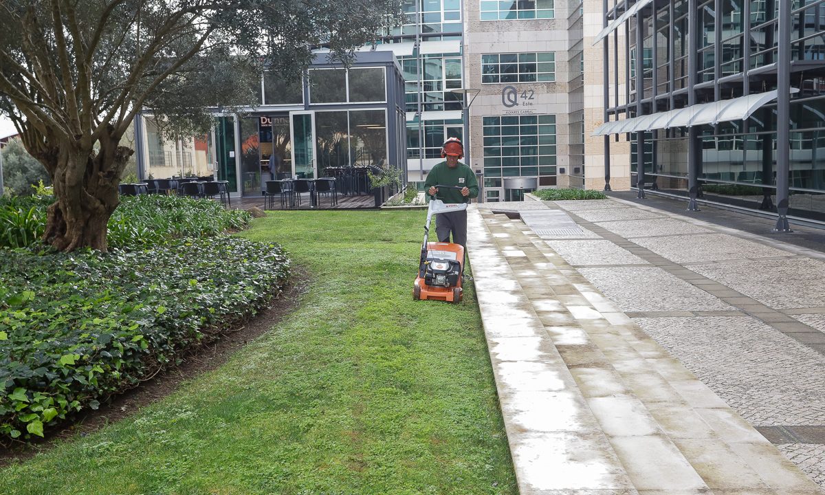Técnico de Jardinagem SAMSIC com uma máquina de cortar relva num espaço de escritórios